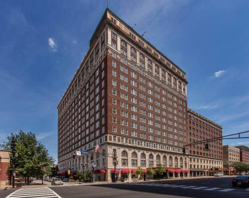 Historic brick hotel building with large windows, set against a clear blue sky, located at a city intersection.