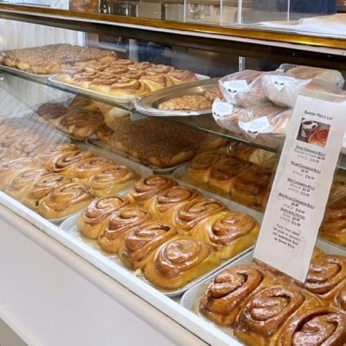 A display case filled with various freshly baked cinnamon rolls and pastries.