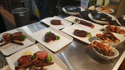 A variety of gourmet dishes, including steaks and sides, beautifully plated on a kitchen counter.
