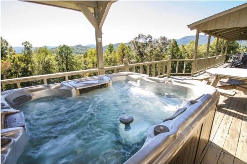 A hot tub on a wooden deck with a scenic view of trees and mountains in the background.