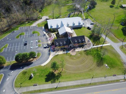 Aerial view of a building with a parking lot, surrounded by green grass and trees.