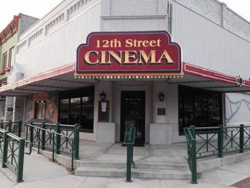 Sign for "12th Street Cinema" on a building exterior, featuring a marquee and decorative elements.