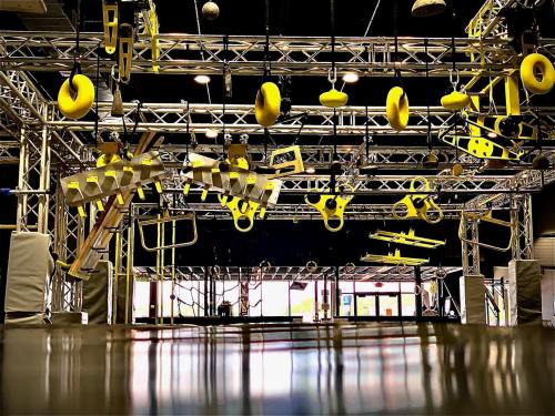 A vibrant indoor obstacle course featuring yellow equipment suspended from a metal frame.