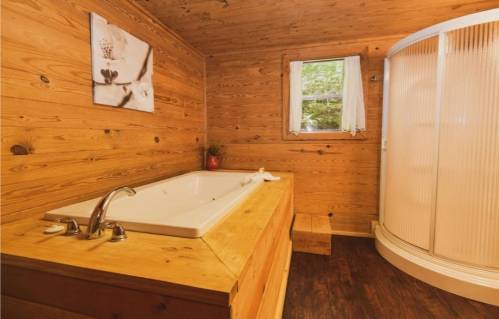 Cozy wooden bathroom featuring a bathtub, shower, and a window with natural light.