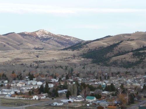 A scenic view of rolling hills and mountains in the background, with a small town nestled in the valley below.