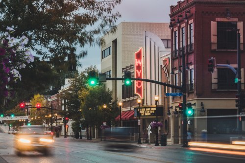 A street scene featuring a vintage theater marquee, traffic lights, and blurred car movement in an urban setting.