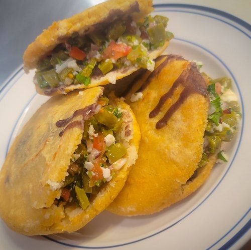 Three stuffed tortillas filled with vegetables and cheese, served on a white plate with a blue rim.