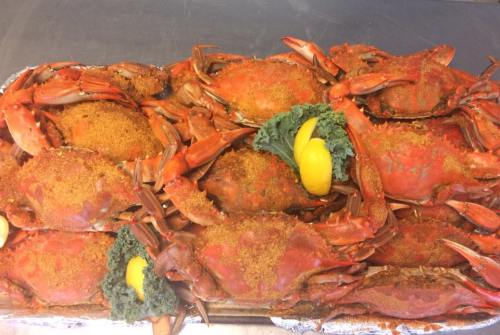 A platter of cooked crabs garnished with lemon and greens, showcasing their vibrant red color and seasoning.