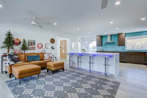 Modern living room with a brown leather sectional, blue bar, and stylish decor, featuring a cozy atmosphere and bright lighting.