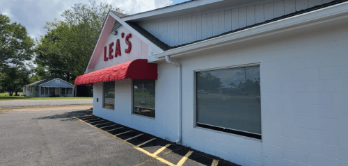 Exterior of Lea's restaurant with a red awning, large windows, and a clear blue sky in the background.