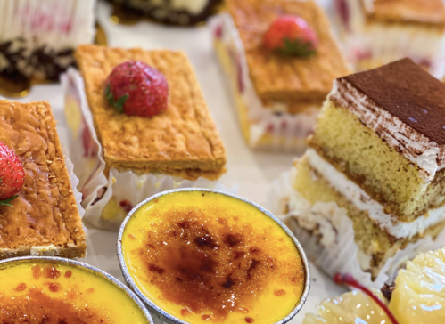 A variety of desserts including layered cakes, pastries, and custard topped with strawberries.