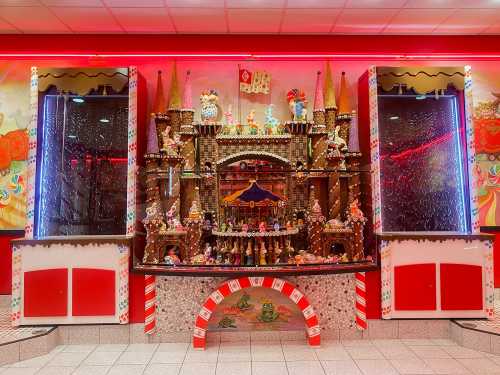 A colorful gingerbread castle display with candy decorations, set against a vibrant, festive backdrop.