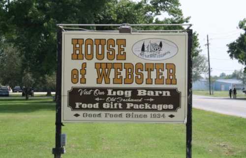 Sign for "House of Webster" featuring food gift packages and a log barn, established in 1934.