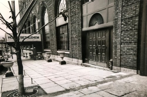 Black and white photo of a brick building exterior with a sign reading "Hotel Bethlehem" and a tree in the foreground.