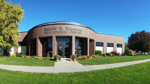 Exterior view of the Harold E. Edgerton Educational Center, featuring a landscaped entrance and clear blue sky.