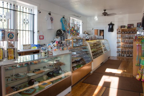 A bright candy shop interior featuring display cases, colorful sweets, and merchandise on wooden shelves.