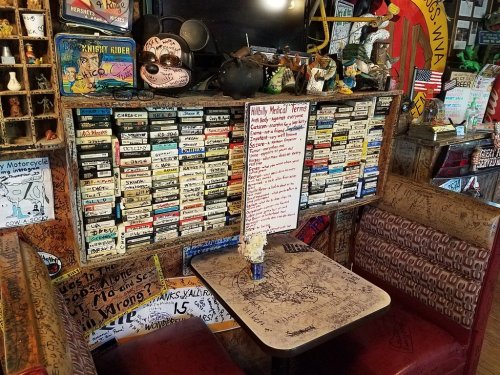 A quirky restaurant interior featuring a table, decorated walls, and a humorous medical terms sign.