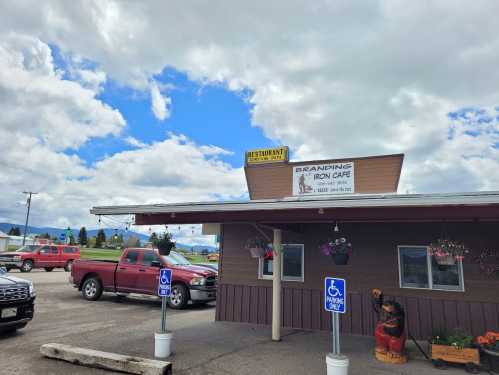 Exterior of Branding Iron Cafe with a sign, parked cars, and a cloudy sky in the background.