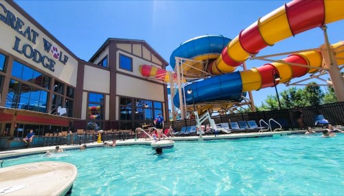 A sunny pool scene at Great Wolf Lodge, featuring colorful water slides and guests enjoying the water.