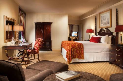 Luxurious hotel room featuring a king bed, elegant furnishings, a desk, and a cozy seating area.