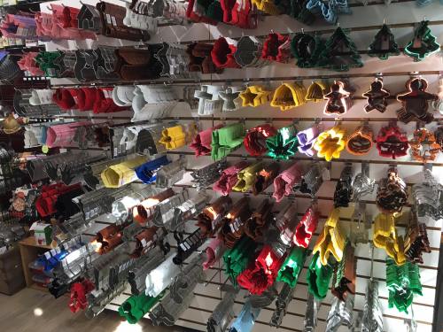 A variety of colorful cookie cutters displayed on a wall, featuring different shapes like trees, stars, and gingerbread men.