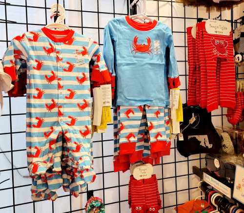 Colorful children's pajamas featuring crab patterns, displayed on a grid wall with various styles and sizes.