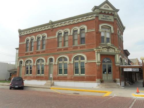 Historic brick building with ornate architectural details, featuring a bank sign and a parked car in front.