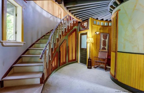 A circular staircase leads to a cozy, uniquely designed entryway with warm colors and decorative walls.