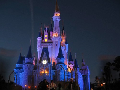A beautifully lit castle at night, featuring tall spires and a magical ambiance in shades of blue and purple.