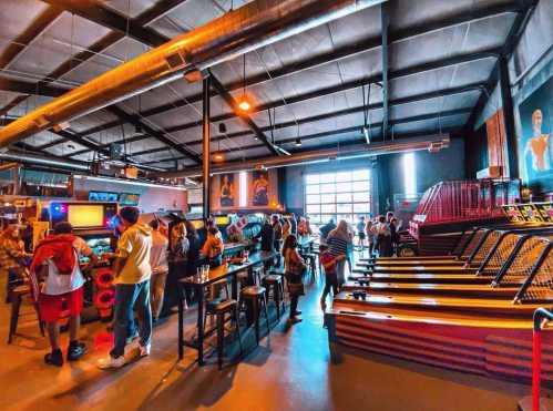 A lively arcade with people playing games, colorful machines, and a vibrant atmosphere.