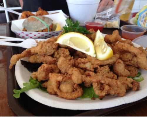 A plate of fried seafood, garnished with lemon slices and served on a bed of lettuce.