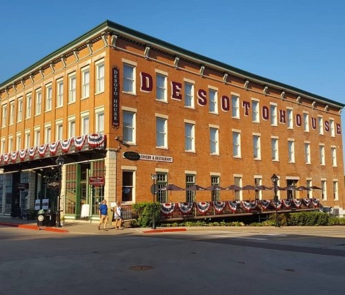 Historic DeSoto House Hotel with red brick exterior, large lettering, and festive bunting along the entrance.
