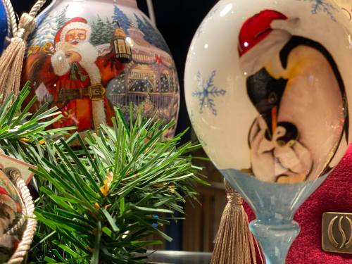 Colorful holiday ornaments featuring Santa Claus and a penguin, surrounded by festive greenery.