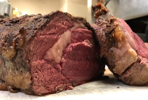 Close-up of a perfectly cooked prime rib, showcasing its juicy, pink interior and crispy outer crust.