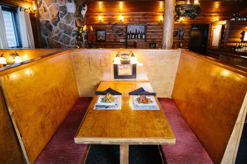 Cozy restaurant booth with two plates of food, warm lighting, and rustic wooden decor.
