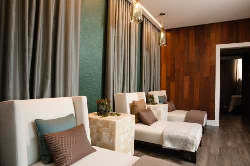 A serene spa lounge with comfortable chairs, soft lighting, and elegant curtains, creating a relaxing atmosphere.