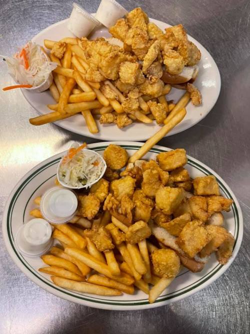 Two plates of golden fried seafood and crispy French fries, accompanied by coleslaw and dipping sauces.