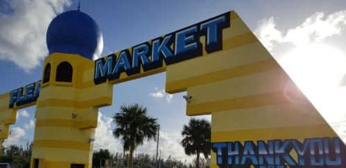 Colorful entrance to a flea market with a blue dome and palm trees, featuring large "MARKET" and "THANK YOU" signs.