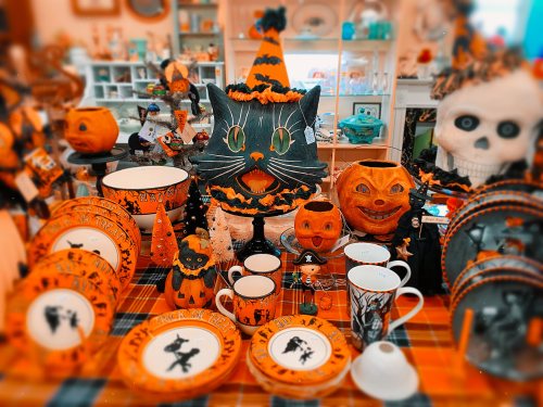 A festive display of Halloween decorations featuring black cats, pumpkins, and themed tableware in orange and black.