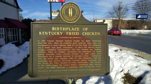 Historical marker detailing the birthplace of Kentucky Fried Chicken and Harland Sanders' contributions to the restaurant industry.