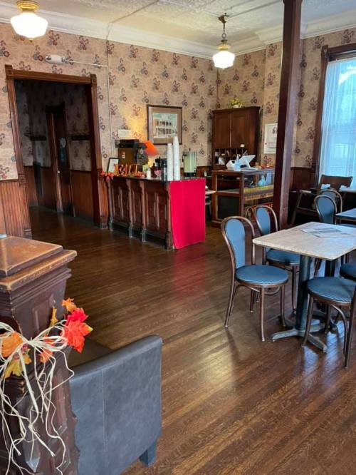 Cozy interior of a café with wooden floors, vintage decor, and tables set for dining.