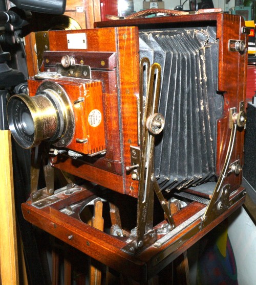 A vintage wooden camera with a bellows design, showcasing intricate metal details and a classic lens.