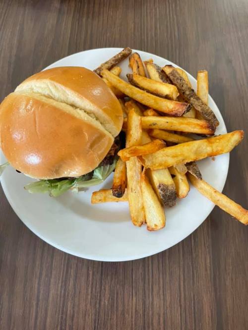 A plate with a burger in a bun and a side of golden, crispy French fries.