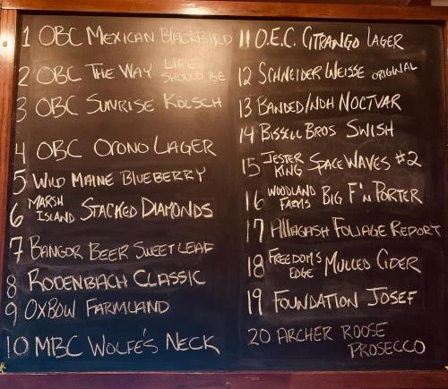 Chalkboard menu listing various beers and ciders with names and descriptions.