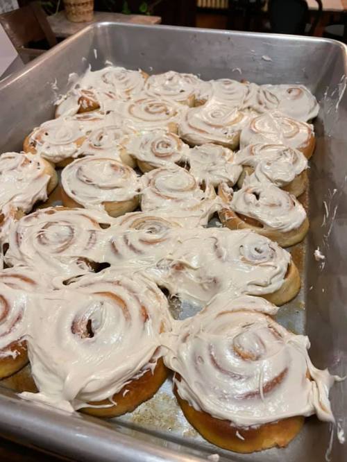 A tray of freshly baked cinnamon rolls topped with creamy white frosting.
