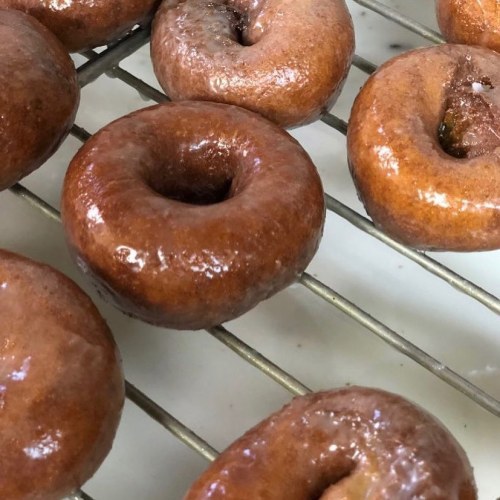 A close-up of freshly glazed donuts cooling on a wire rack.