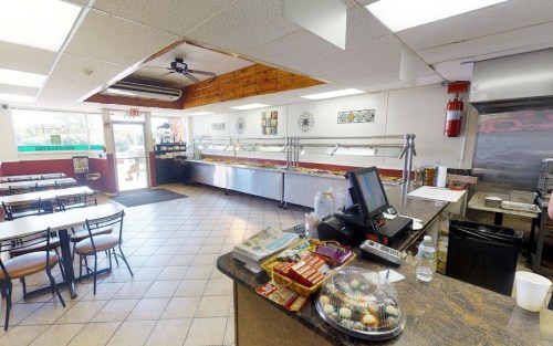 Interior of a casual dining restaurant with a buffet, tables, and a counter with a cash register.