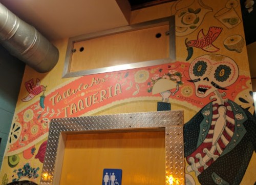 Colorful mural featuring a skeleton and floral designs, with the text "Tallecah's Taqueria" above a door.
