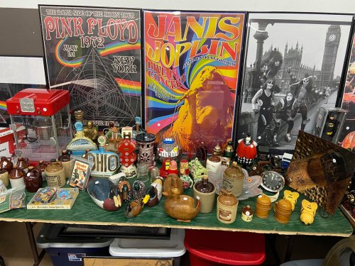 A display of vintage memorabilia, including posters of Pink Floyd and Janis Joplin, alongside various collectibles and souvenirs.