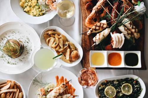 A beautifully arranged seafood feast with various dishes, including grilled seafood, pasta, and colorful sauces.